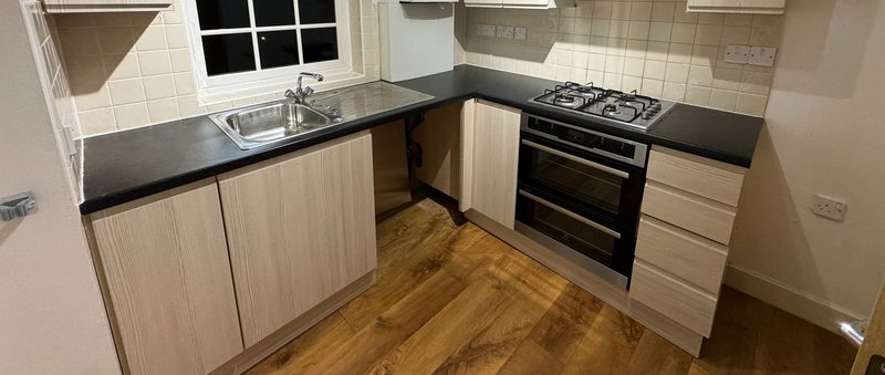 Kitchen in Broughton Gate with new pale wood-grain doors and drawer fronts, a black worktop and a gas hob