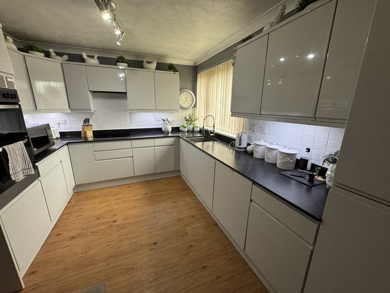 Kitchen in Newton Longville after the work: light grey gloss handle-free doors, a dark worktop, white metro tiles and a cornice along the wall units
